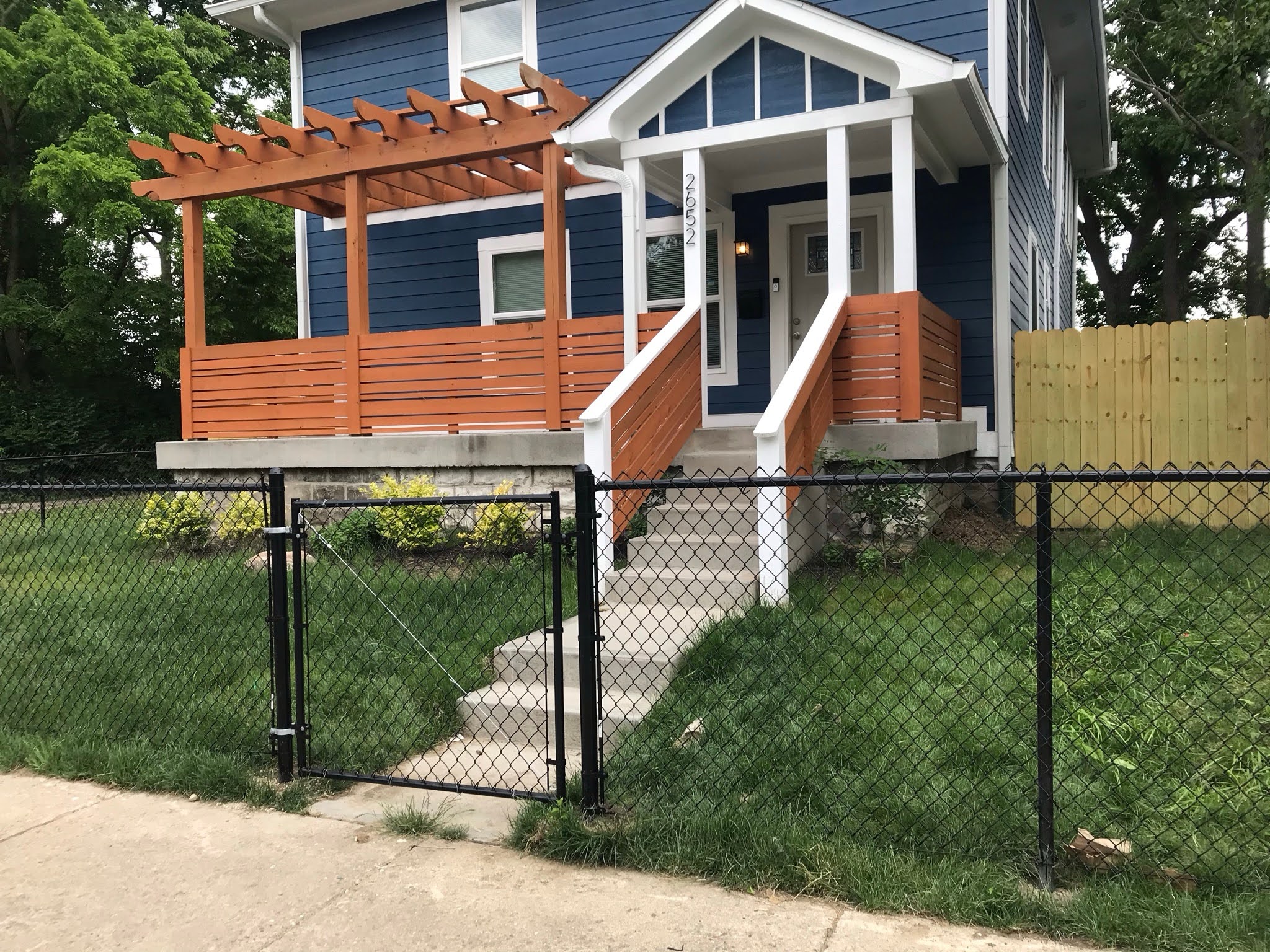 Black vinyl coated chain-link fence and gate across a front yard